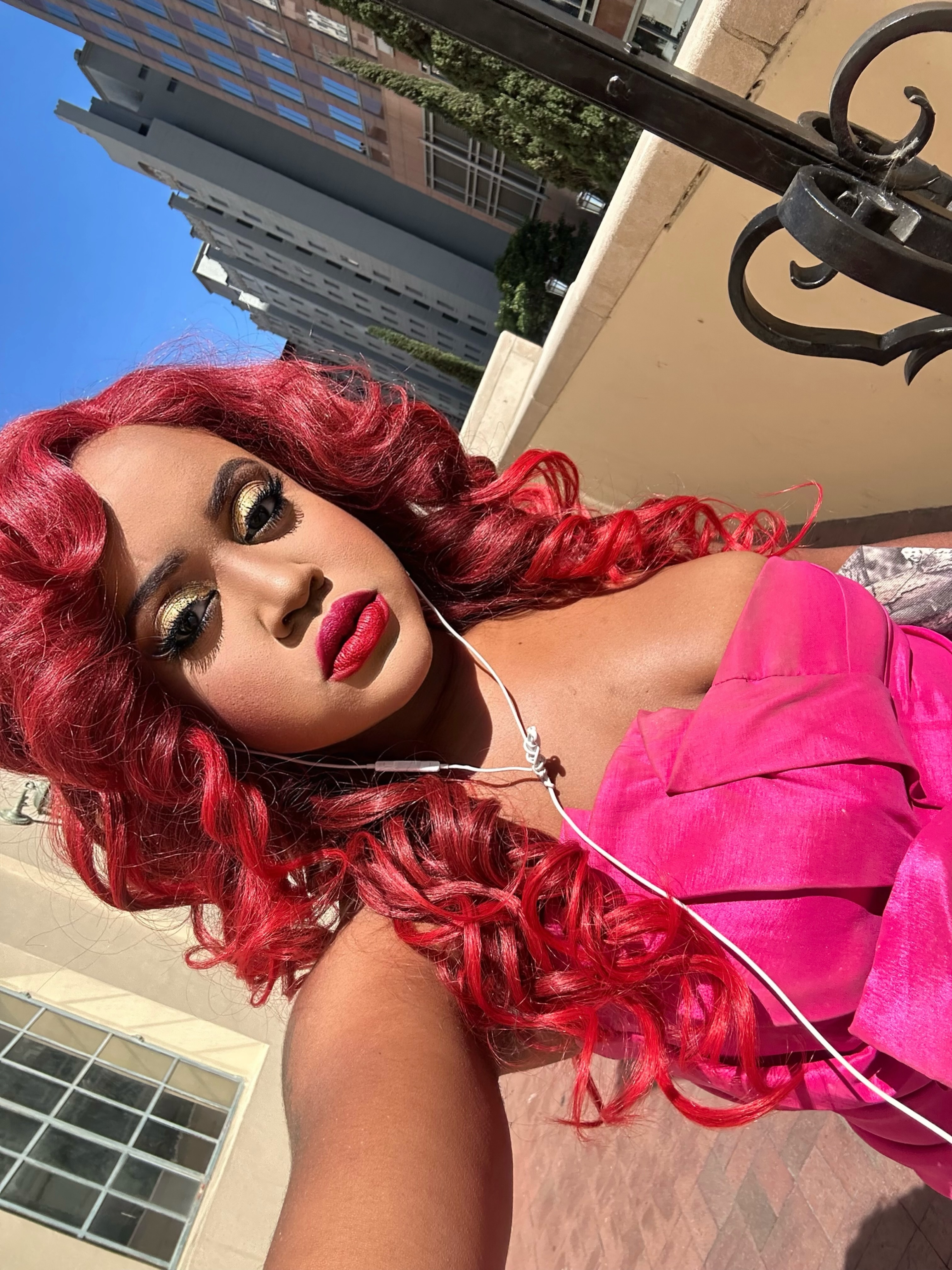 Samantha Samaka on a balcony, red curls and pink top